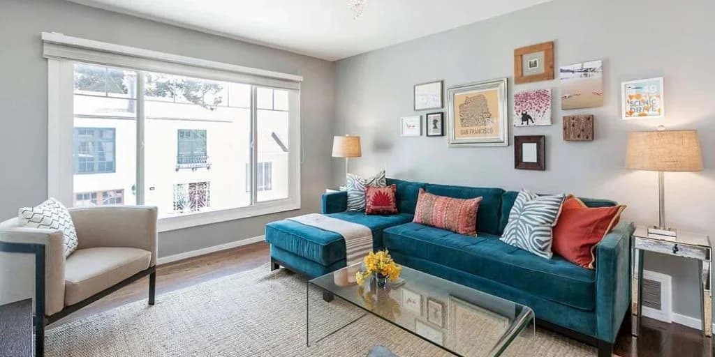 A finished living room with softly painted walls, a teal sofa and a framed picture wall