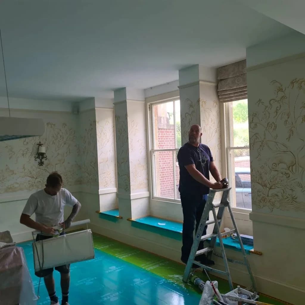 Two Bourne Decorators decorators at work in a hand-painted mural room, floors and window sills fully sheeted and taped before painting