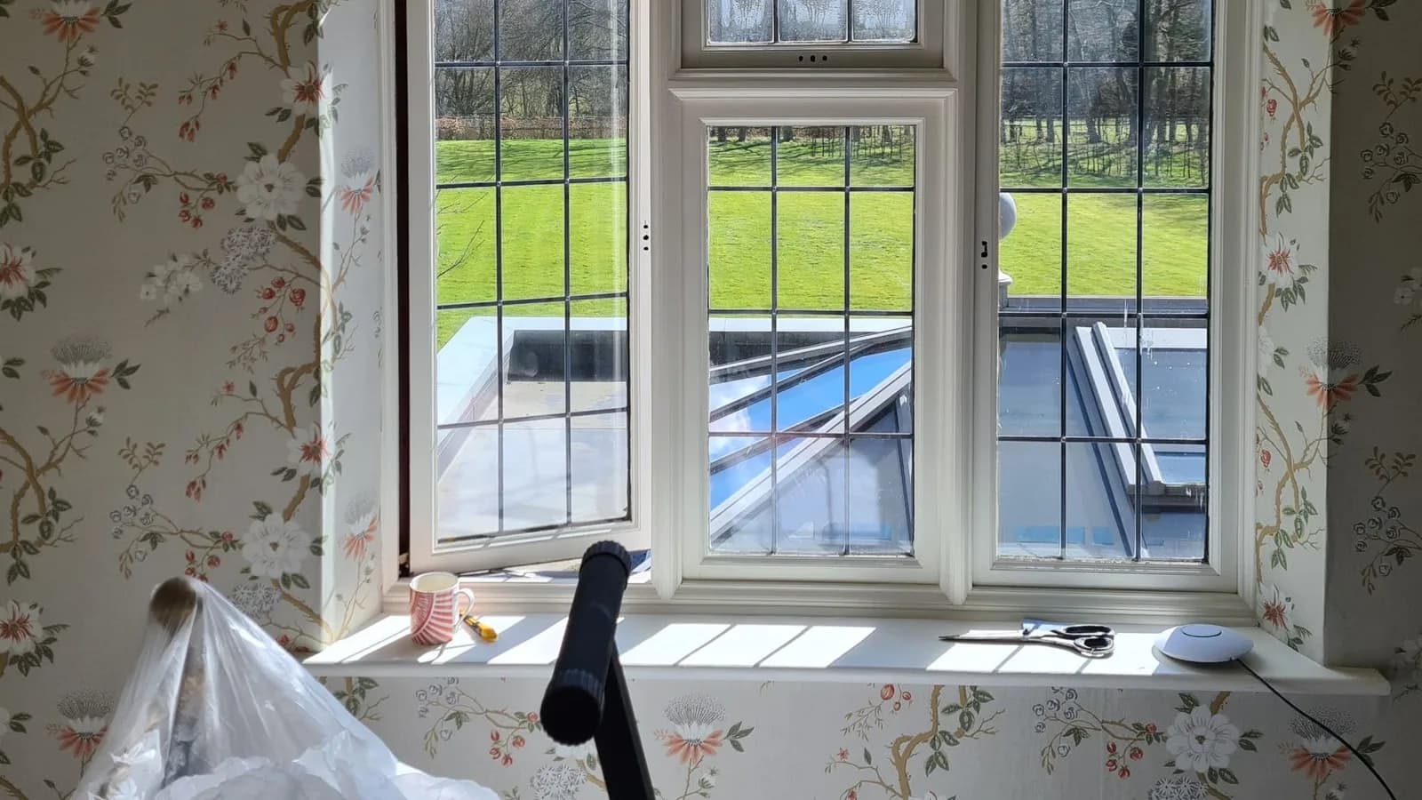 Floral chinoiserie wallpaper hung around leaded windows overlooking the garden, a Bourne Decorators wallpapering project