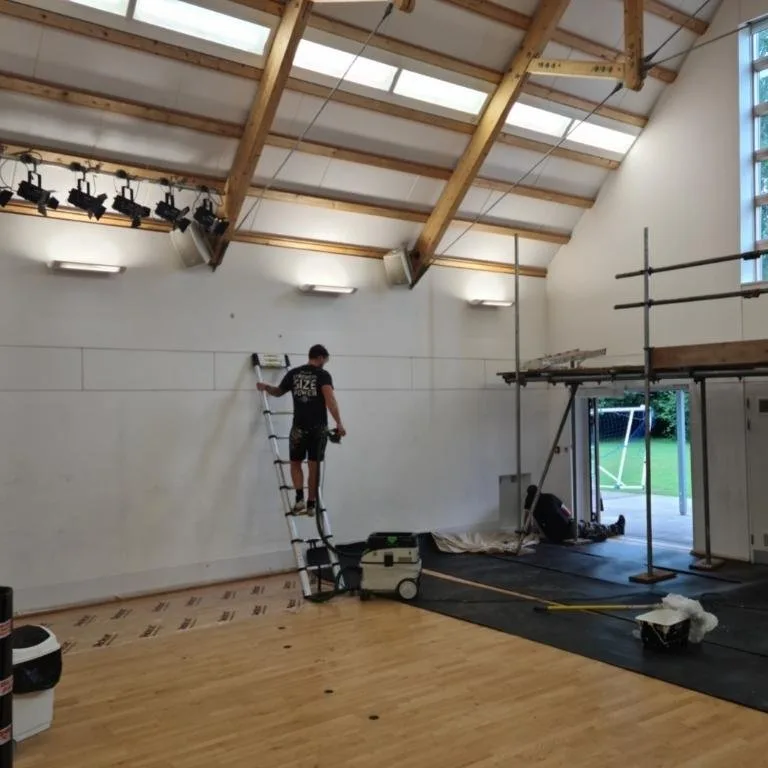 Bourne Decorators repainting a village hall interior from an extension ladder, commercial decorating project